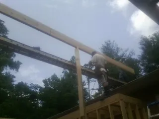 Carpenter setting a ridge beam over a new addition frame — Ice Dam Removal by Roofing Brothers in Swanville