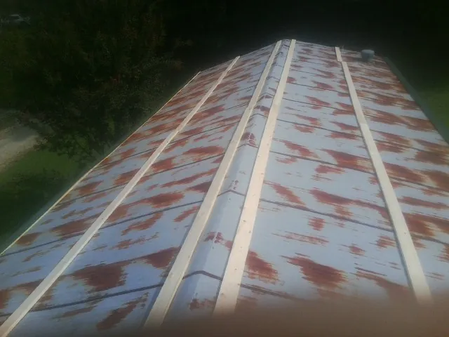 Rusted metal roof panels with new wood purlins before replacement — Storm Damage Roof Repair in Swanville by Roofing Brothers