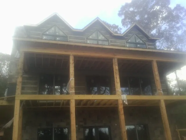 Dormers and porch framing on a large log home under construction — Roof Coating work by our crew in Swanville
