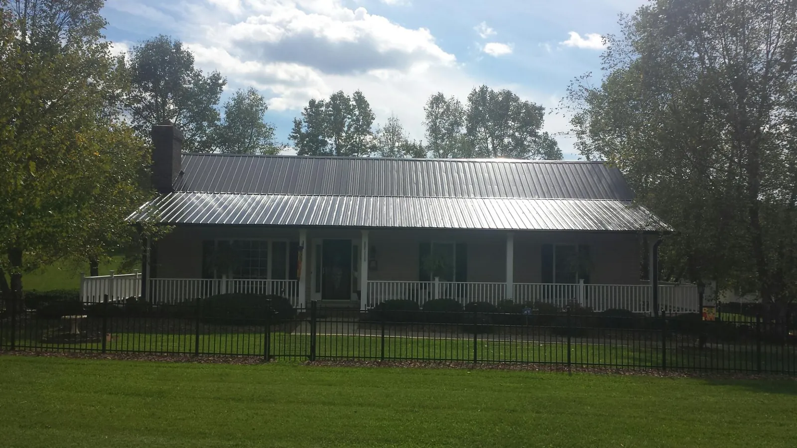 Gray metal roof on a brick ranch with a full width front porch — Gutter Guard Installation work by our crew in Swanville