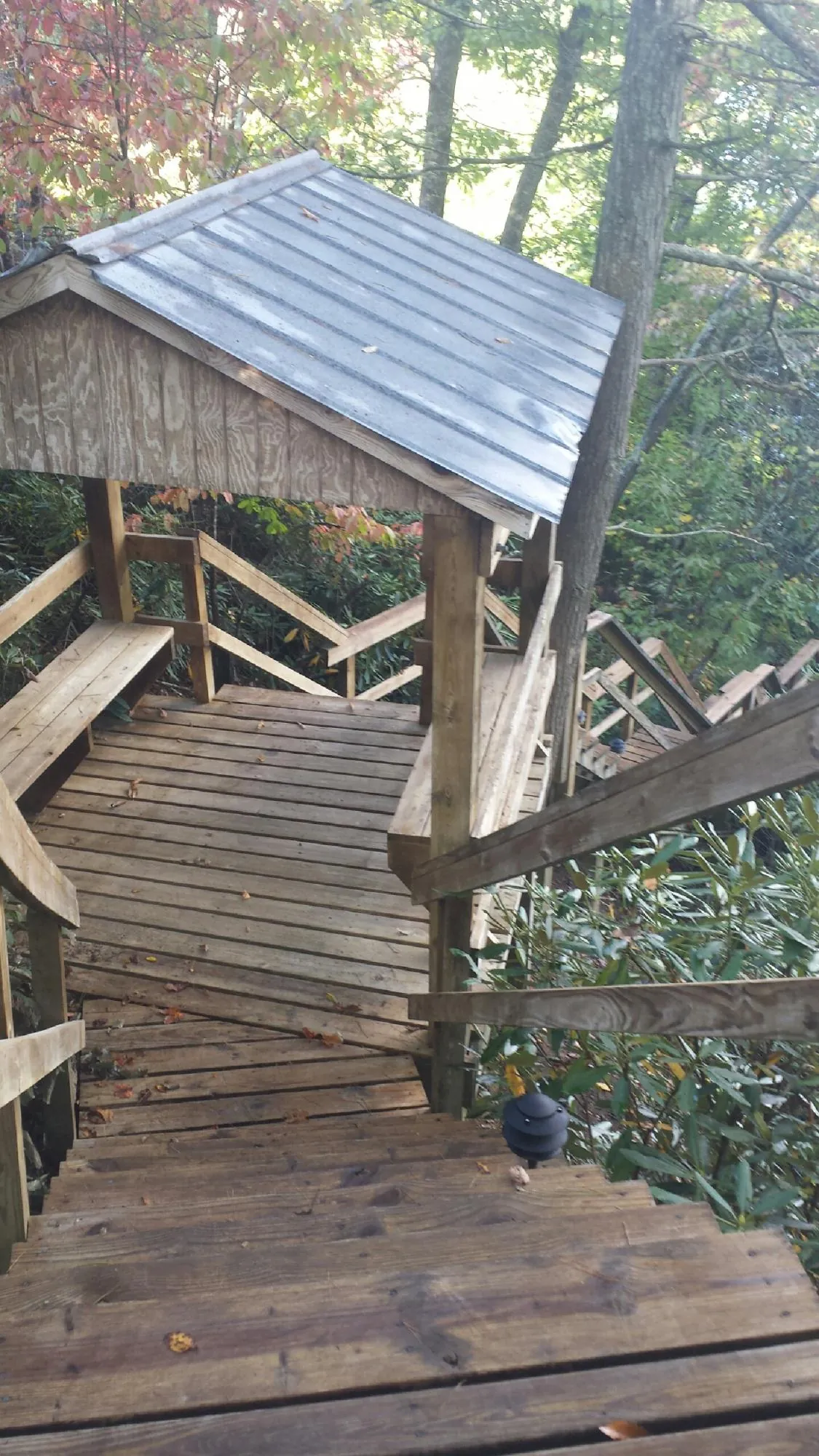 Metal roofed shelter over wooden steps on a wooded walkway — Skylight Repair & Installation work by our crew in Swanville