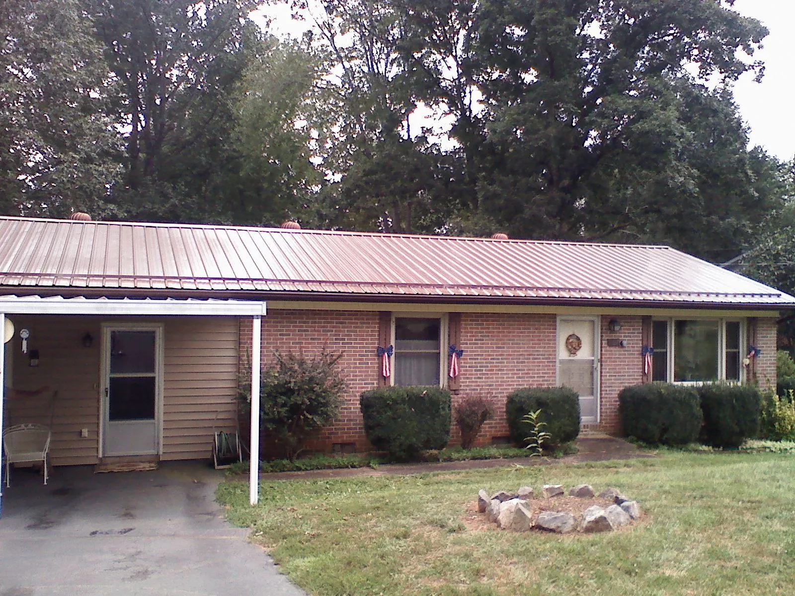 Bronze metal roof and carport on a brick ranch home — Roof Repair work by our crew in Swanville