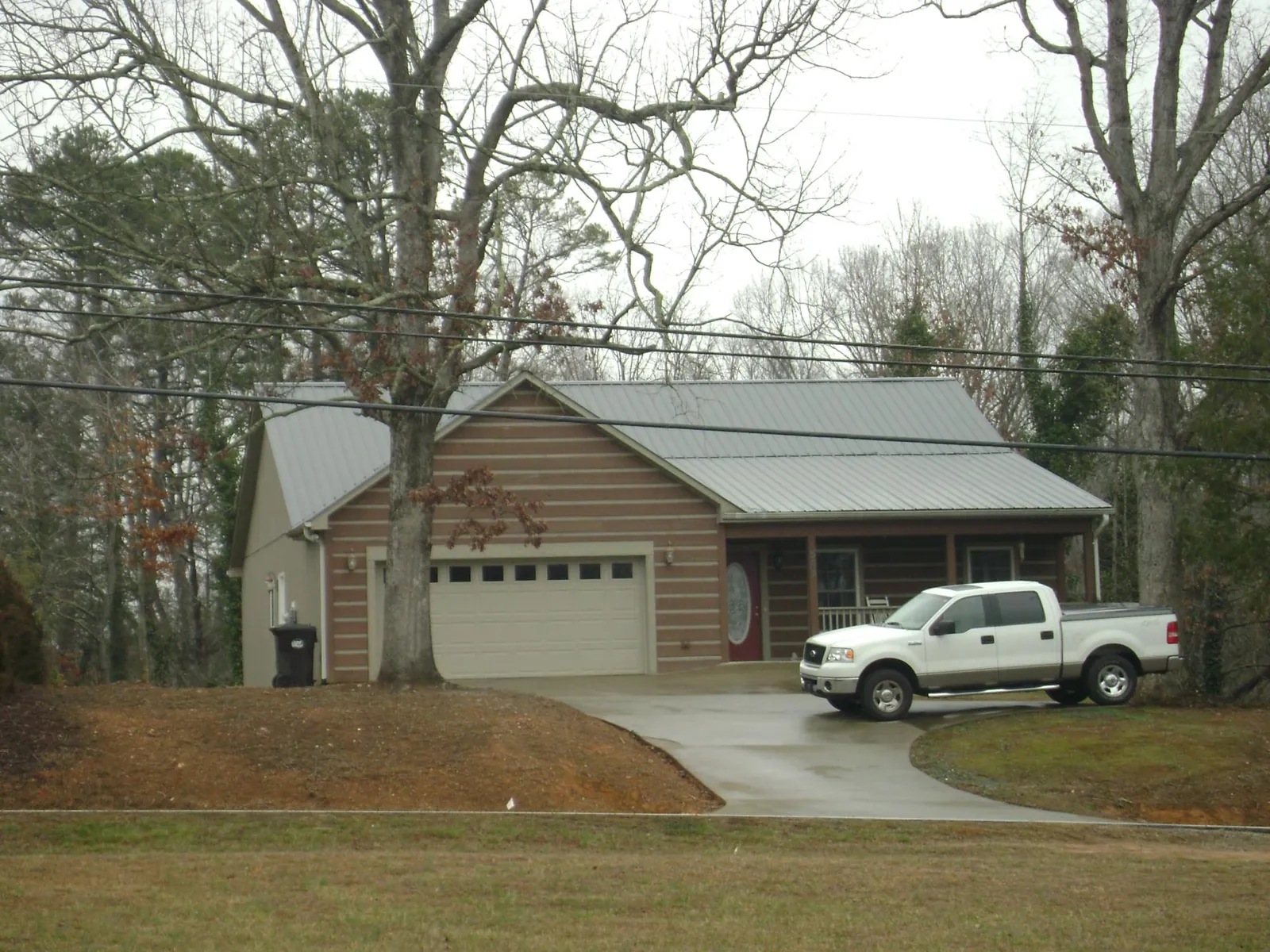 Gray metal roof on a log sided house with an attached two car garage in Swanville