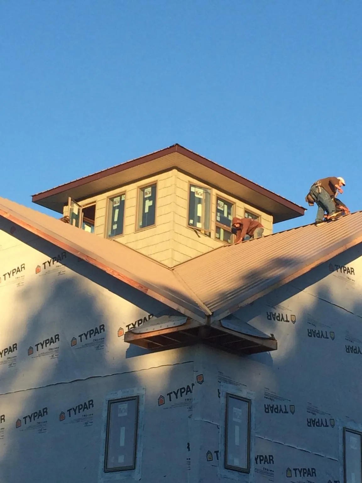 Roofers working around a rooftop cupola on a new metal roof at sunset — Roof Waterproofing in Swanville by Roofing Brothers